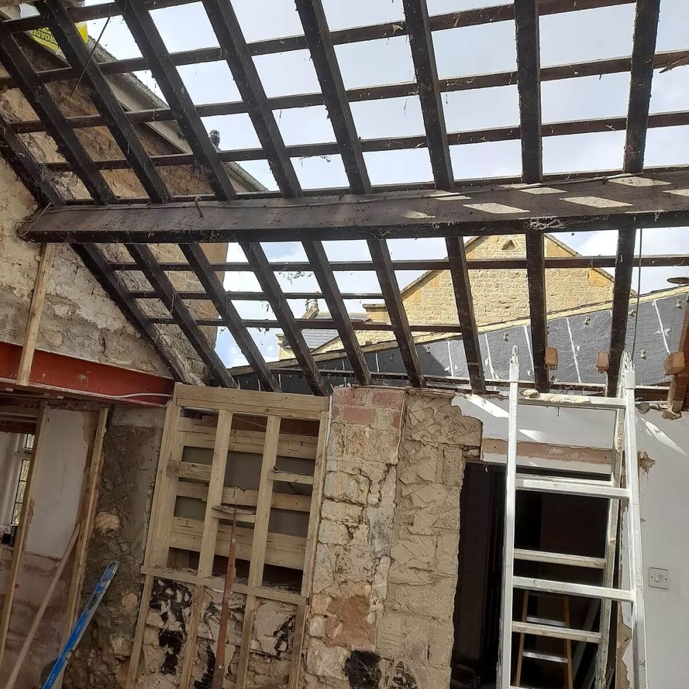 House refurbishment in progress with exposed roof structure and stone walls