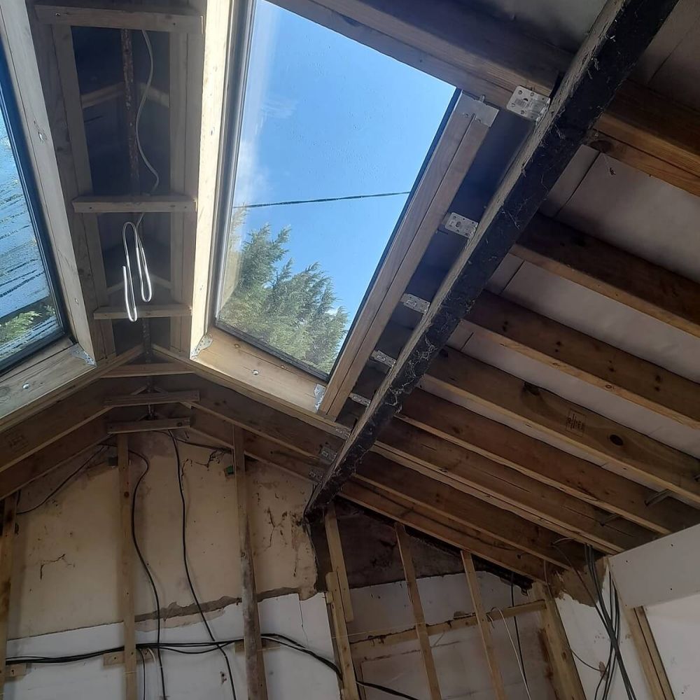 Roof refurbishment interior showing new timber structure and rooflight installation