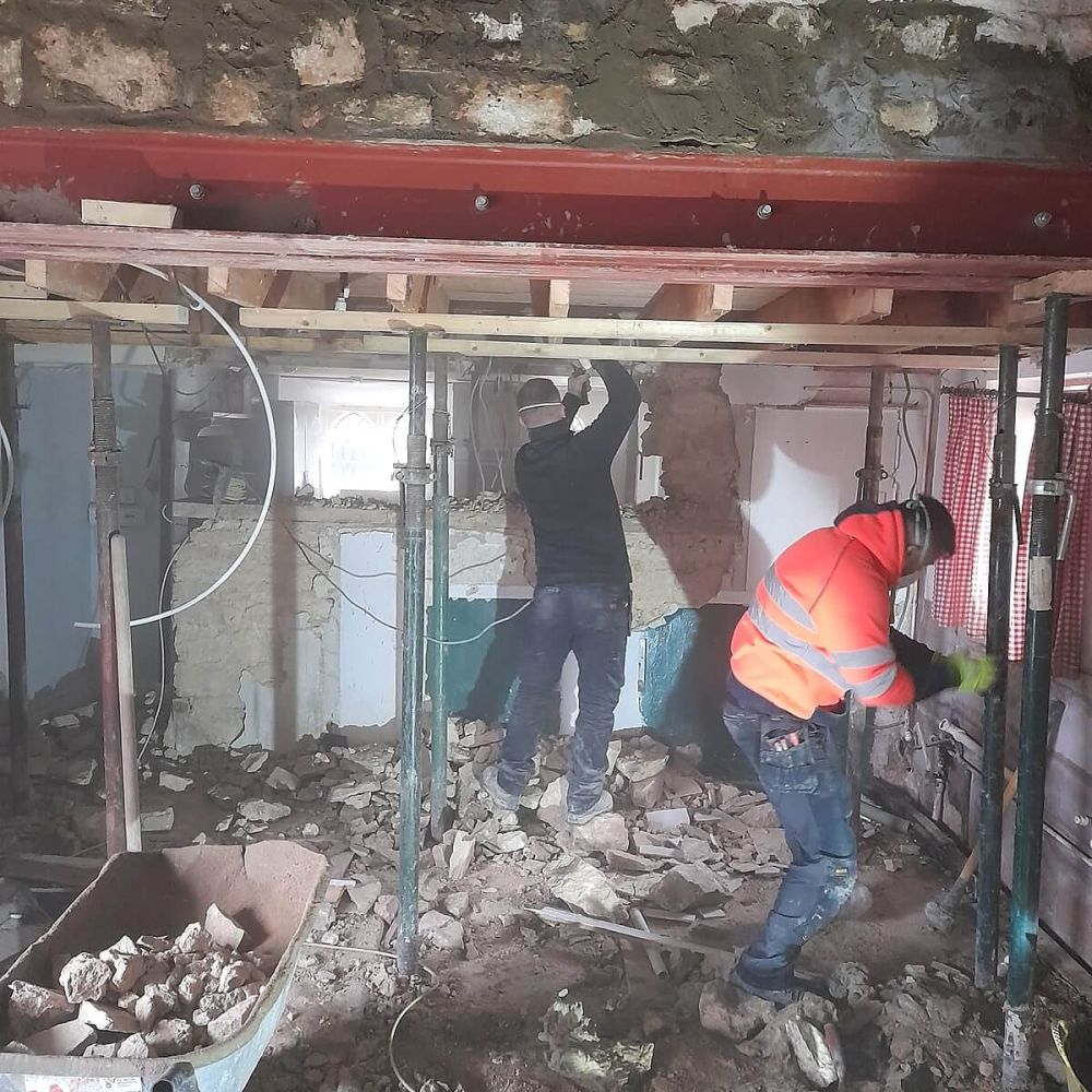 Structural renovation work inside old stone house with steel beam and builders